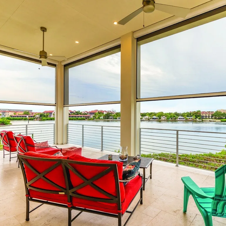 Partially lowered screens integrated into the openings of a covered waterfront balcony.
